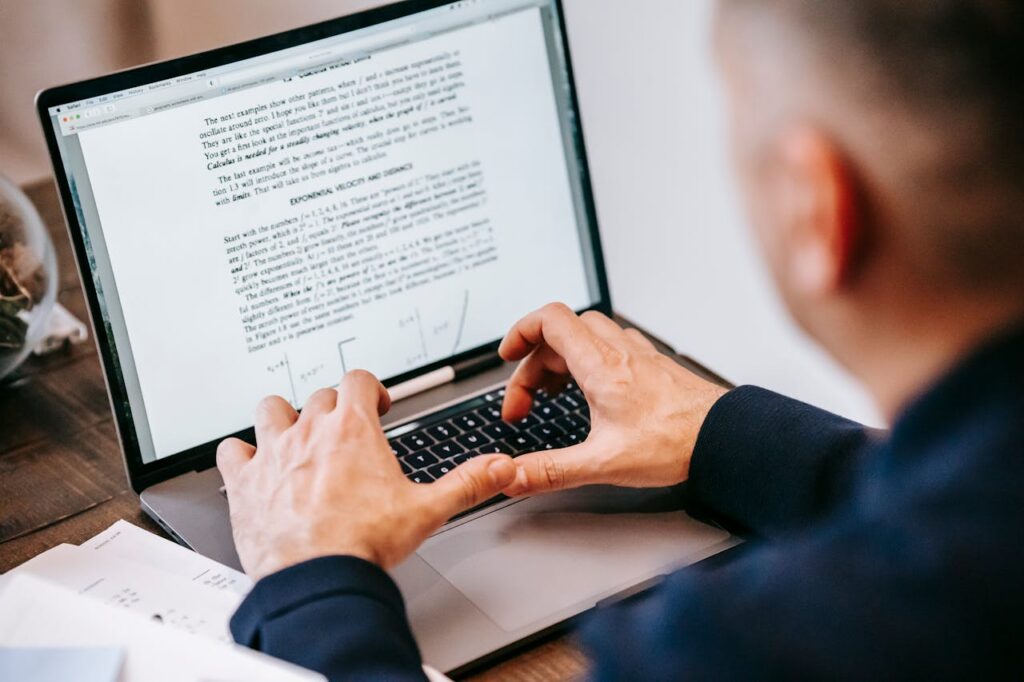 Man typing on laptop at home office, focused on work, illustrating remote work lifestyle.